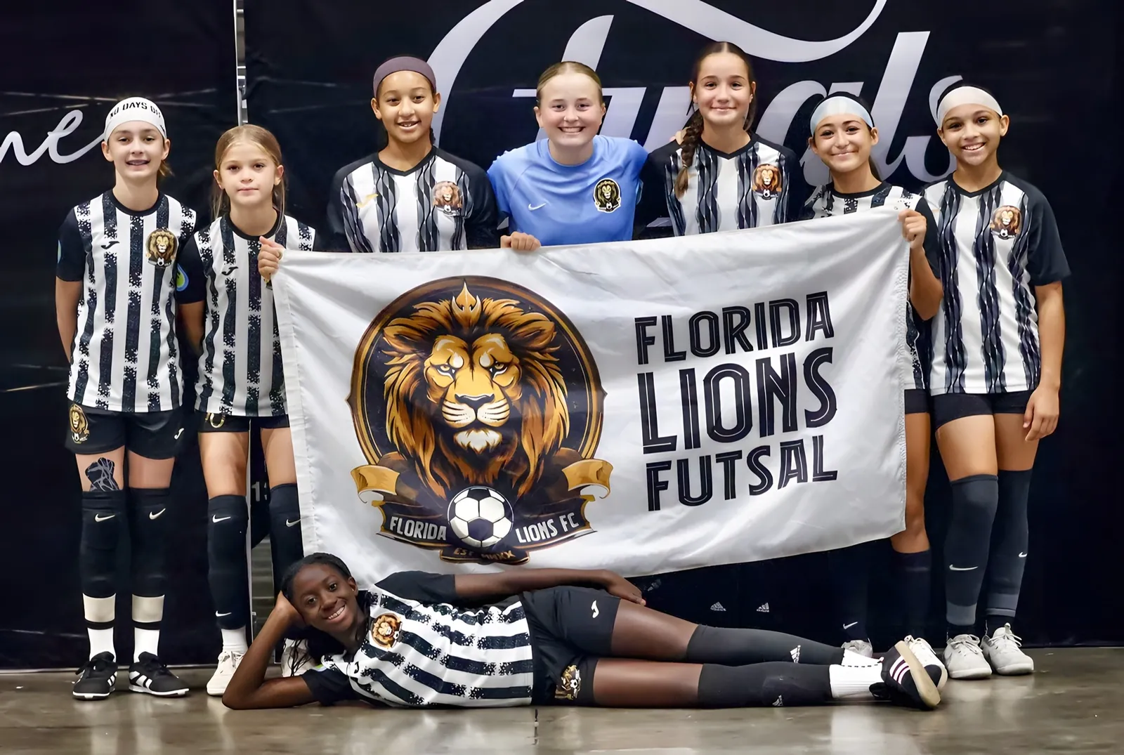 Florida Lions U13 girls with the club banner at the United Futsal Worlds